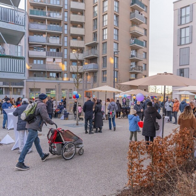 Blick in den Innenhof einer Wohnanlage in dem viele Familien mit Kindern zusammenstehen und feiern.